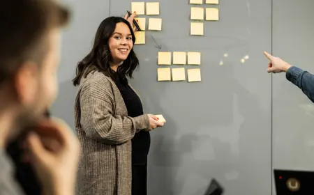 Kvinna står vid en whiteboard tavla och ler