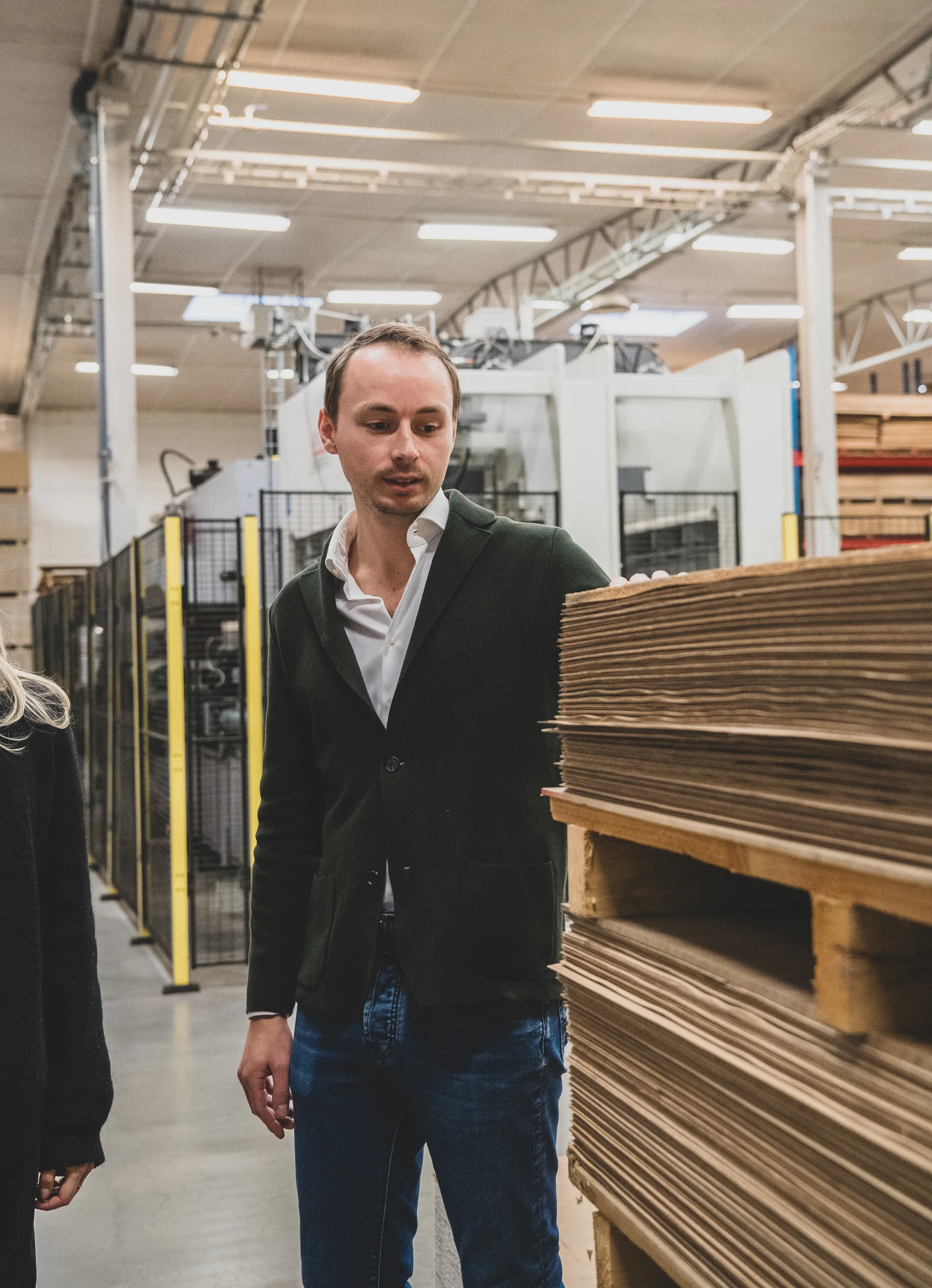 Pontus Davidsson står i produktionen bredvid staplade golvprodukter.