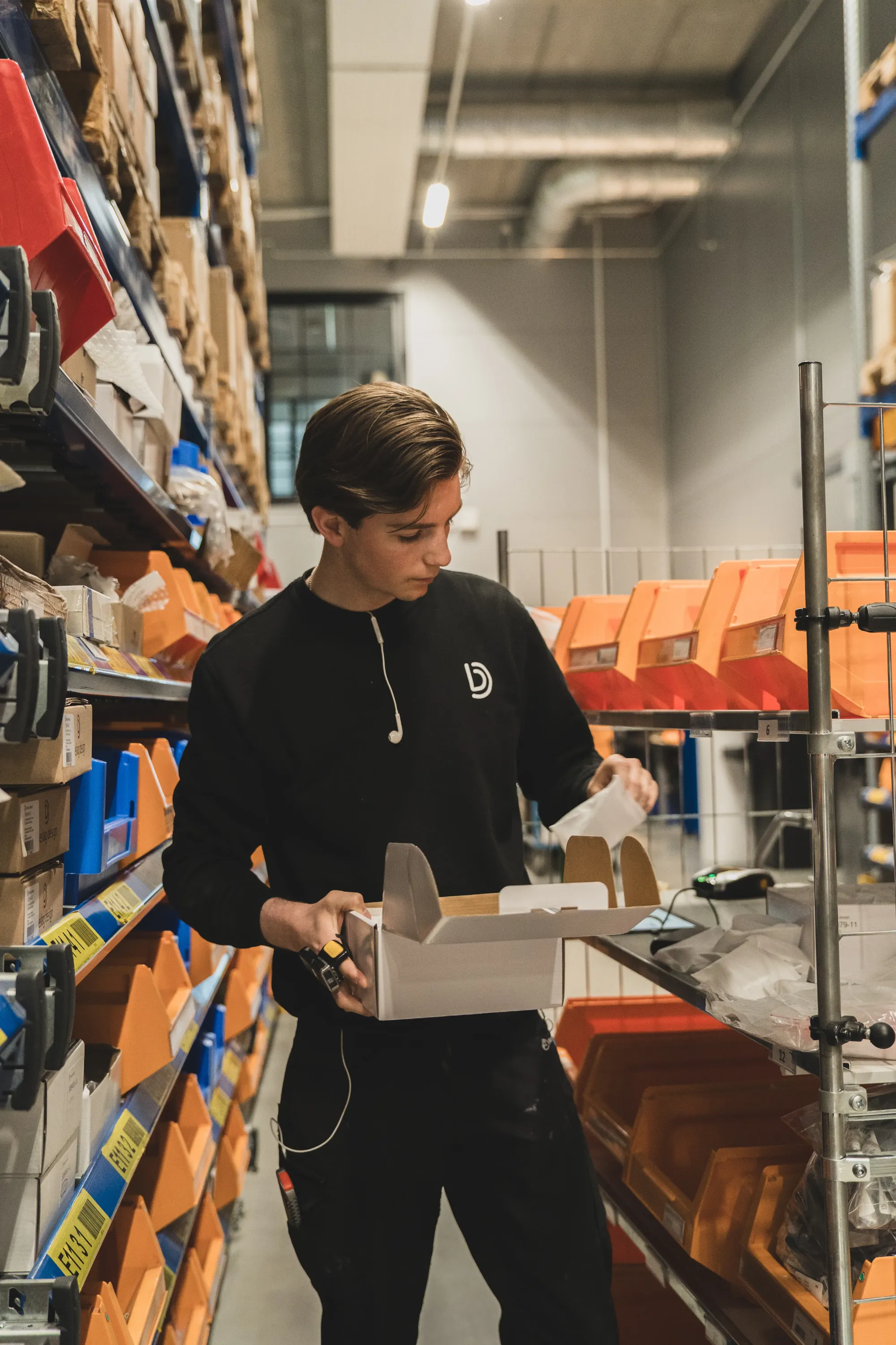 Ung man plockar order för hand i Beslag Designs lager.