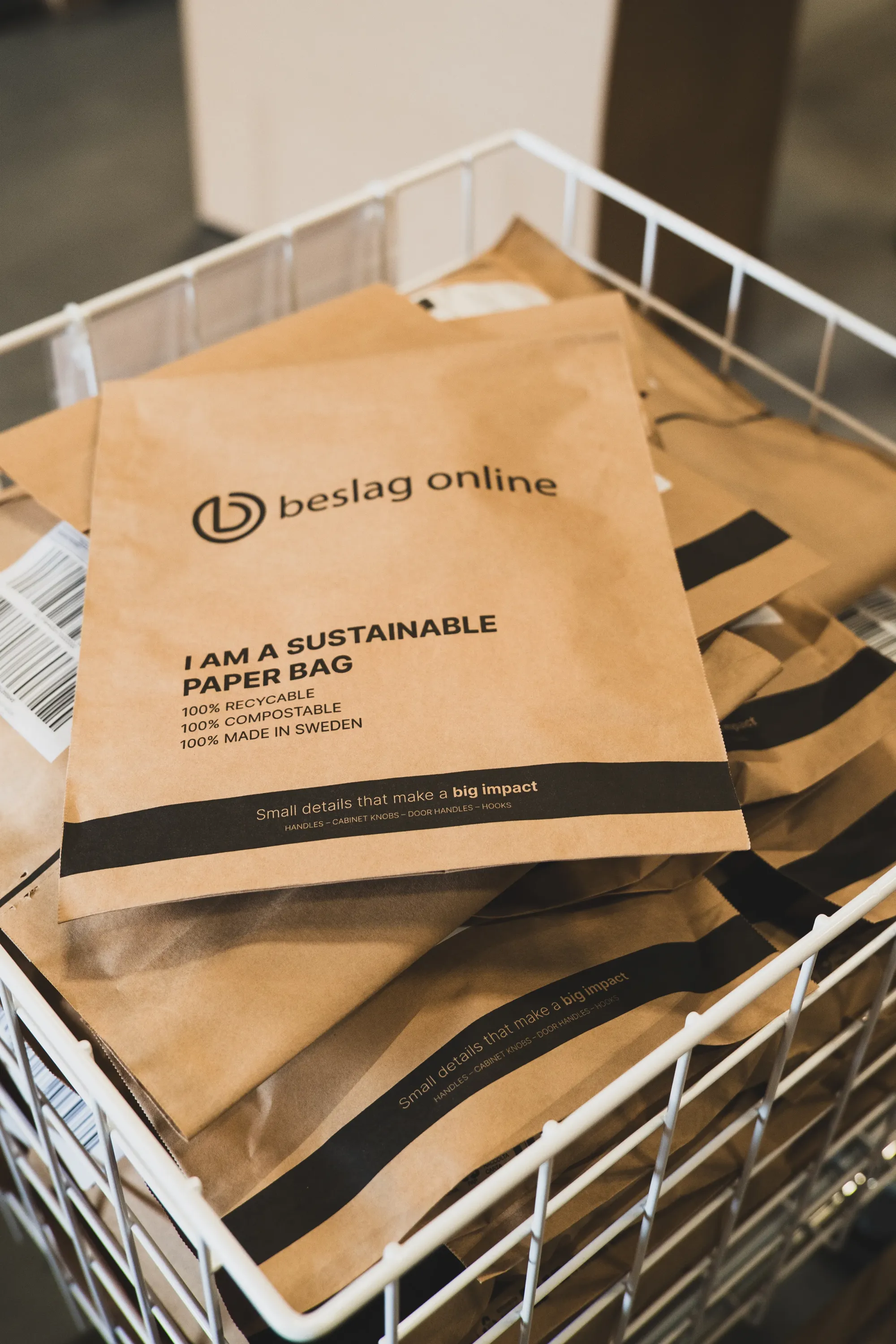 Staplade bruna papperspåsar märkta med Beslag Designs varumärke och texten "I am a sustainable paper bag".