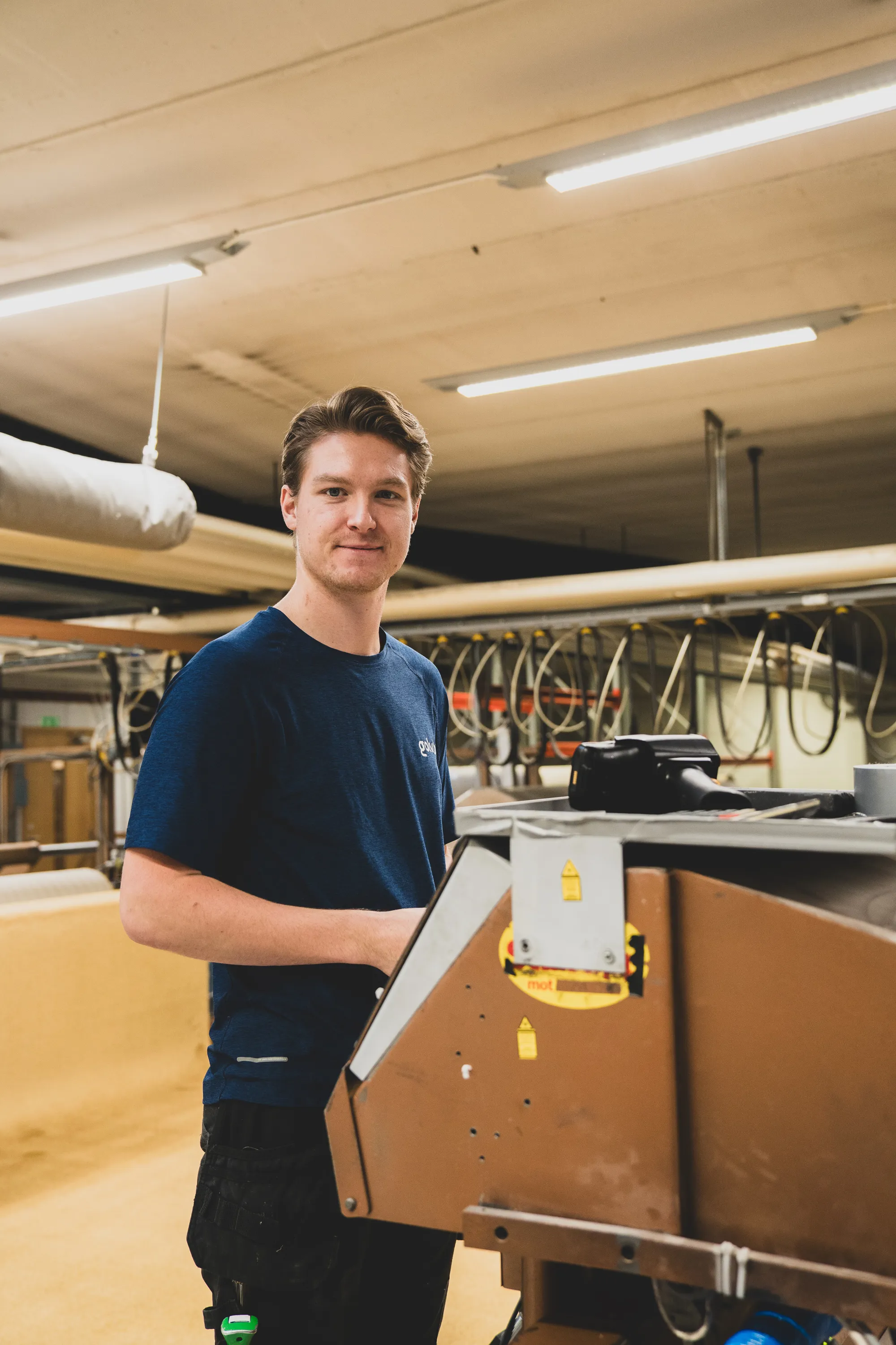 Medarbetare i produktionen som arbetar med mattproduktion vid en maskin.