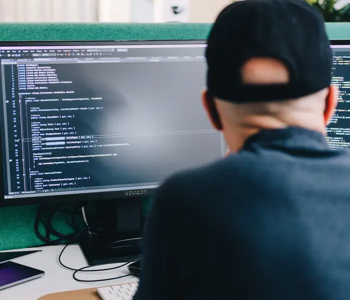 En bild på en dator med kod på skärmen och en person som utvecklar integrationen mellan Pyramid och Litium