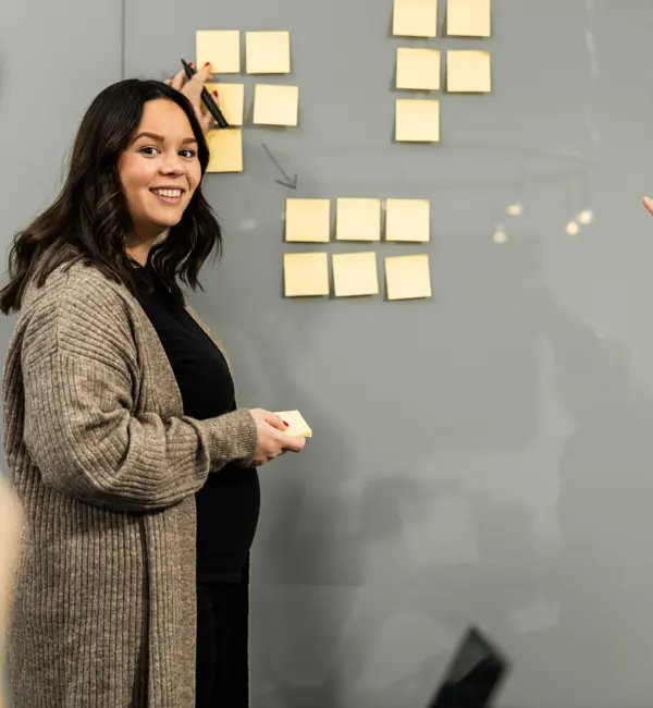 Kvinna står vid en whiteboard tavla och ler