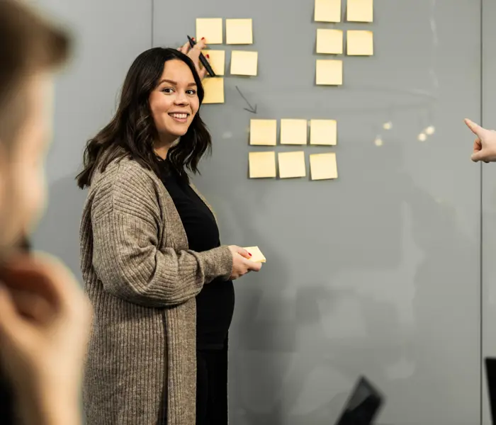 Kvinna står vid en whiteboard tavla och ler