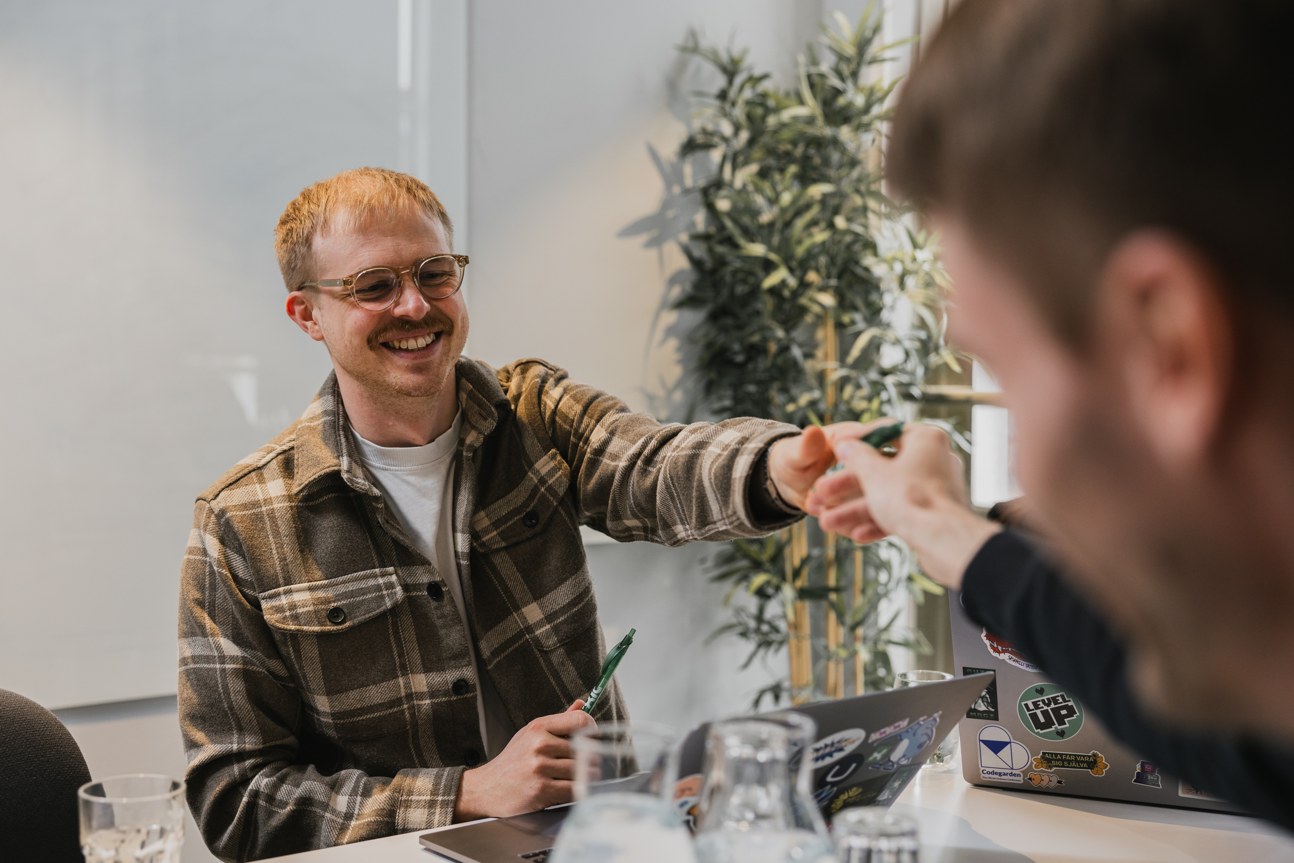 Two colleagues at Toxic fist bump during a meeting at a table with laptops.