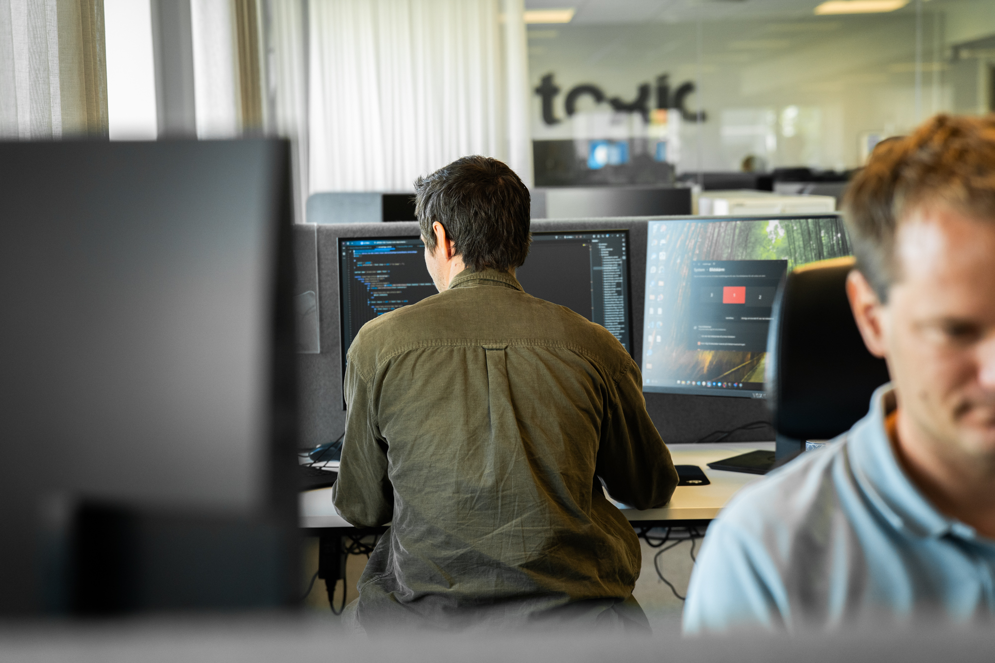 En bild på en dator med kod på skärmen och en person som utvecklar integrationen mellan Pyramid och Litium